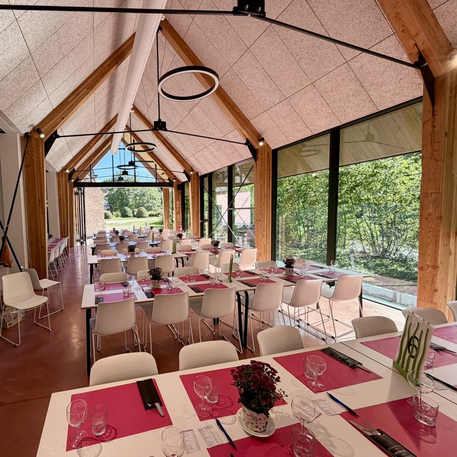 Les tables dress&eacute;es dans le Koetshuis, avec vue sur la verdure du domaine